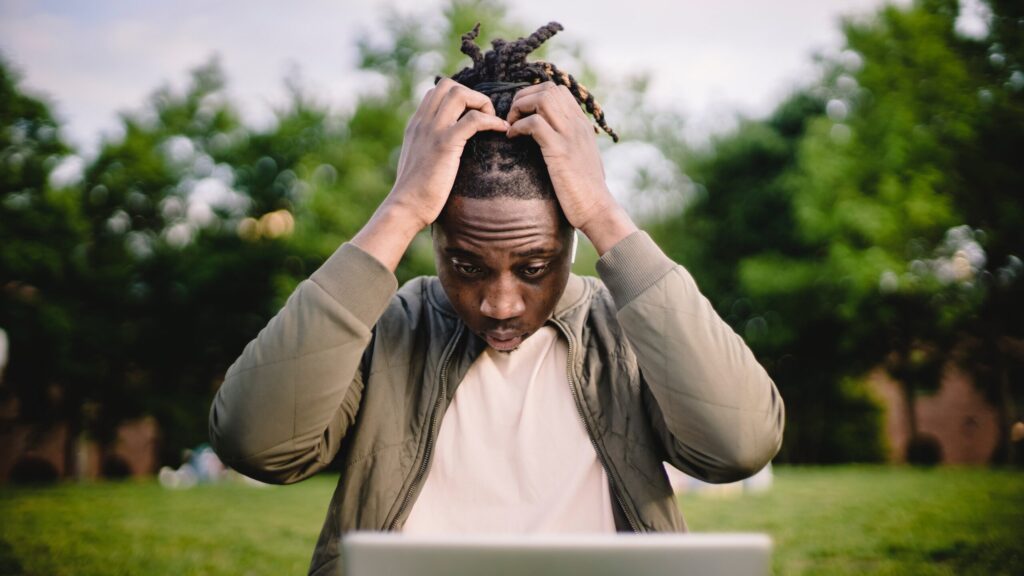 A man with both of his hands brought to his head, looking distressed